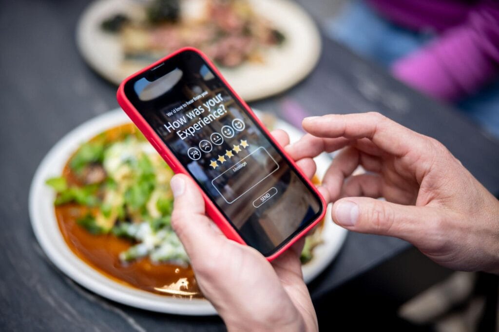 Customer leaving a five-star restaurant review on a smartphone as part of effective marketing strategies for restaurants.